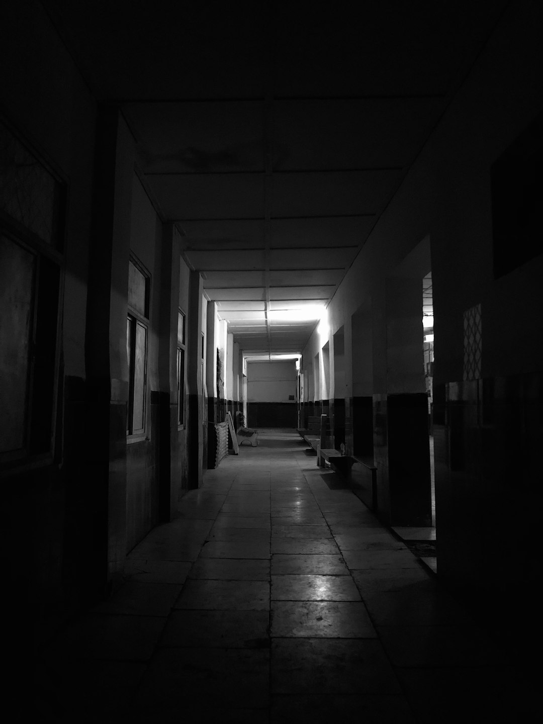 a dark hallway with a light at the end of it