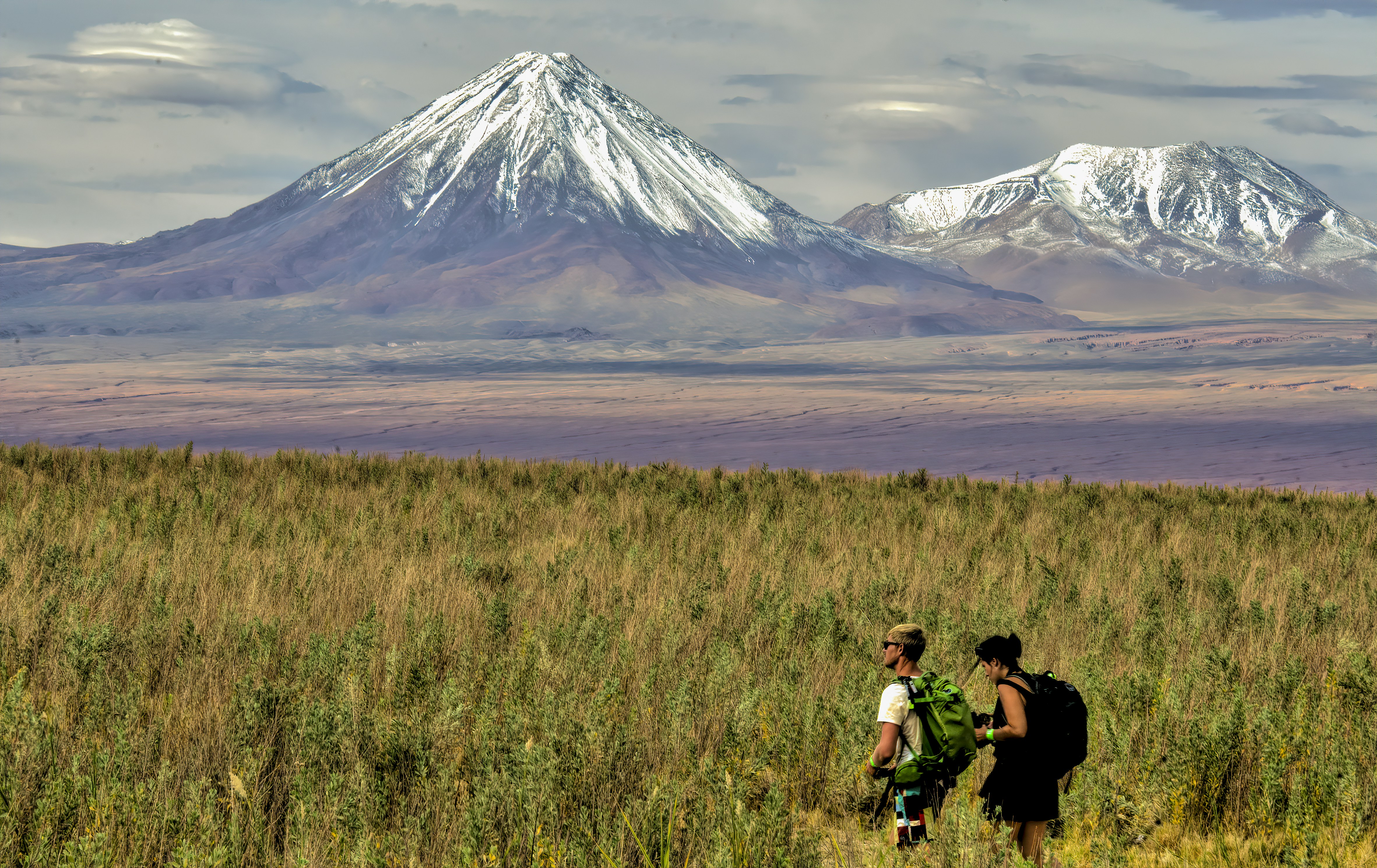 man and woman sitting on grass field near mountain during daytime